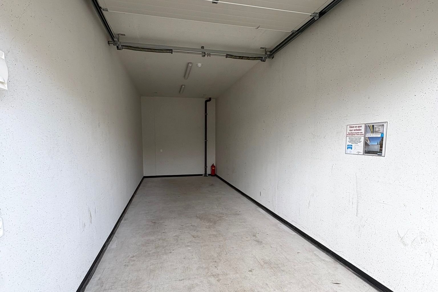 Ruim interieur van de garagebox met betonnen vloer en TL-verlichting